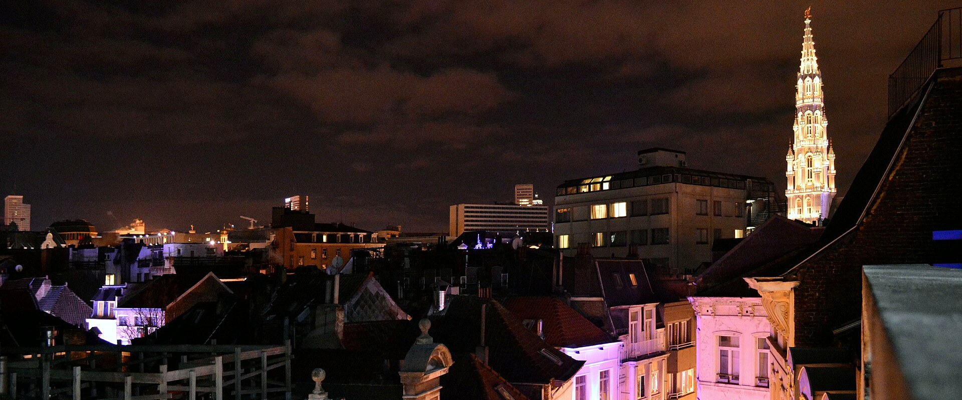 Toits de Bruxelles illuminés la nuit, avec la tour de l'Hôtel de Ville